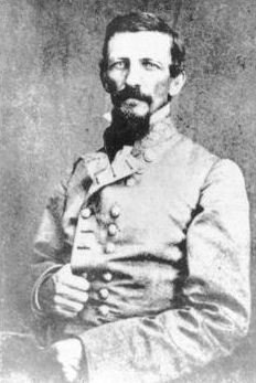 صورة بالأبيض والأسود تُظهر رجلاً ذا شارب ولحية. يرتدي زياً عسكرياً رمادياً بصفين من الأزرار.