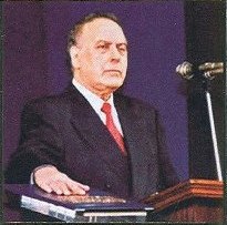 علييف يقف على المنصة ويده على كتاب