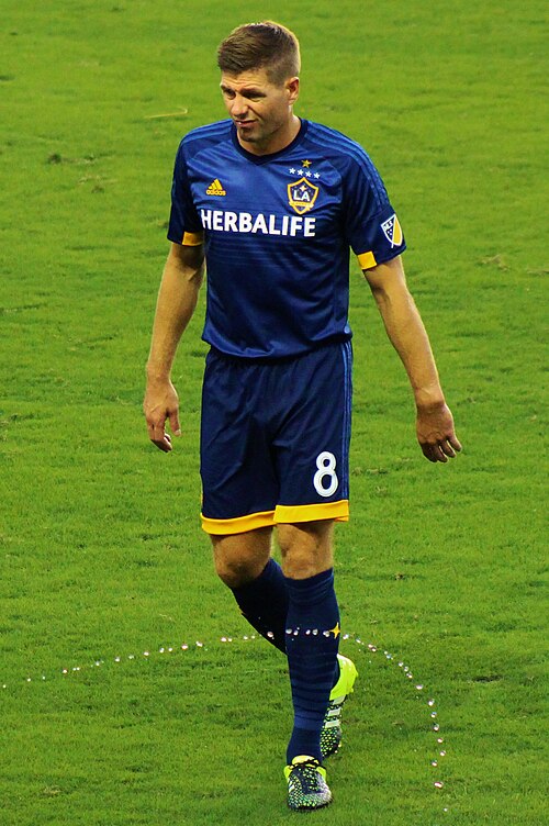 غارارد يسير عبر الملعب مرتدياً طقماً أزرق داكناً مزيناً بحواف صفراء