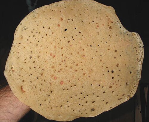 خبز دائري رقيق ذو فقاعات وثقوب كثيرة.