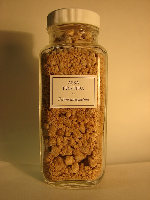 قطع من الراتنج بأحجام مختلفة ولون بني وردي في قارورة تحمل علامة "Assa foetida – Ferula assa-foetida".