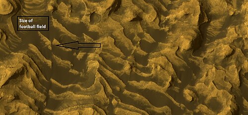 صورة مكبرة للصورة السابقة تُظهر صدعًا وطبقات. تم التقاط الصورة باستخدام كاميرا HiRISE، ضمن برنامج HiWish.
