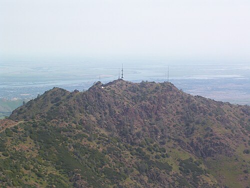 قمة جبلية صخرية مغطاة جزئياً بالغابات، وتضم العديد من هوائيات الاتصالات.