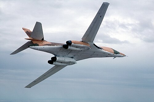 طائرة من طراز B-1A تحلق وأجنحتها ممدودة للأمام، مما يُظهر جانبها السفلي الأبيض المضاد للوميض