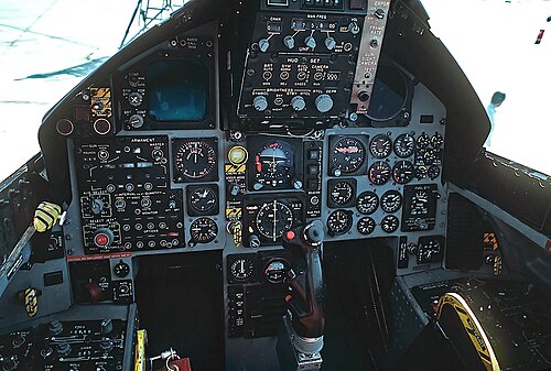 قمرة قيادة طائرة مقاتلة نفاثة مزودة بمؤشرات وعدادات دائرية: يبرز عصا التحكم من بين المكان الذي توضع فيه ساقا الطيار.