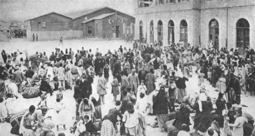 تجمع حشد كبير من الناس في ساحة المدينة، حاملين بعض ممتلكاتهم.