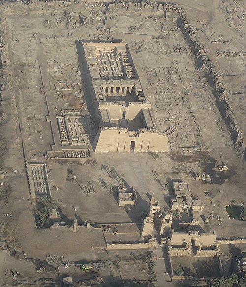 مبنى حجري مستطيل الشكل من الأعلى، مع ساحات وأبراج في الواجهة وبقايا جدران في الخلف. يحيط بالمبنى الرئيسي جدار مستطيل وأساسات مبانٍ أخرى.