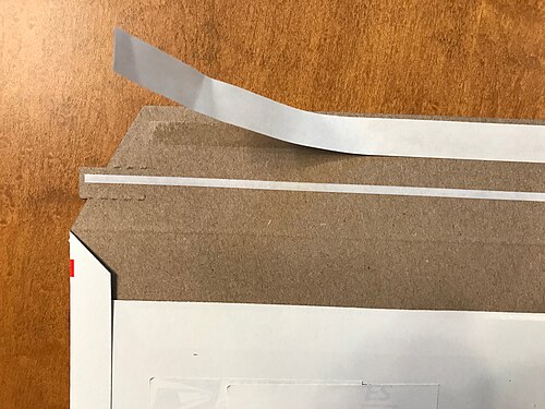 ظرف بريدي من الورق المقوى يظهر عليه لاصق PSA مع بطانة قابلة للفصل وشريط قابل للتمزيق