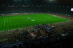حاملو الأعلام يدخلون الملعب، يليهم لاعبو الفريقين، الزمالك والزوراء، بالإضافة إلى حشد من الصحفيين والمصورين، خلال حفل الافتتاح