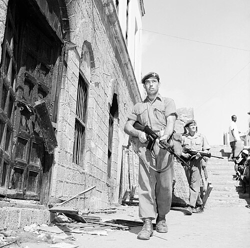 جنود فوج المظليين في عدن عام 1956 يرتدون الزي العسكري الكاكي والقبعات، مع معدات حمل مقتصرة على جيوب الذخيرة.