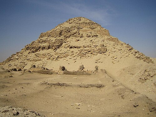 هرم عظيم ولكنه مدمر، مصنوع من الطوب والحجارة في الصحراء.