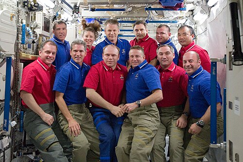 أفراد طاقم STS-132 (الذين يرتدون قمصانًا زرقاء) وأفراد طاقم البعثة 23 يقفون لالتقاط صورة جماعية على متن محطة الفضاء الدولية.