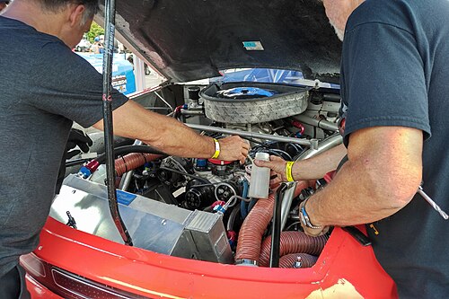 محرك V8 مزود بمكربن. يوجد رجلان على كل جانب من المحرك يعملان عليه.