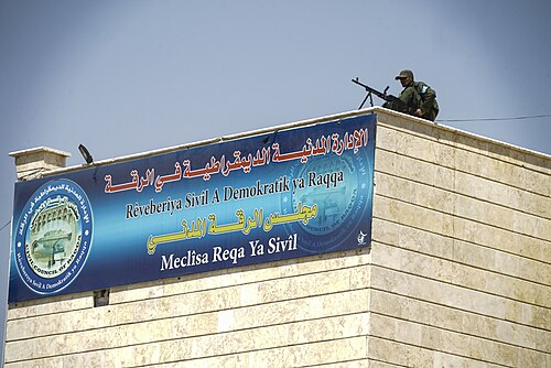 شرطي من قوات الأمن الملكية العراقية يوفر الحماية أعلى مبنى المجلس المدني في الرقة، 18 أغسطس 2018