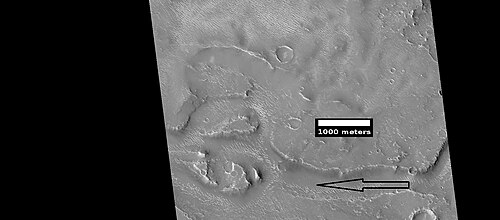 Close view of streamlined shapes, as seen by HiRISE under HiWish program Arrow indicates the direction of past flowing water.