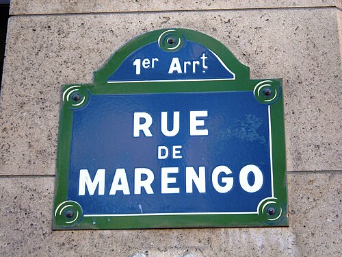 لافتة شارع زرقاء ذات حواف خضراء. مكتوب عليها باللون الأبيض: "1er Arrt" وتحتها "RUE DE MARENGO".
