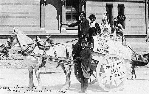 هذه صورة لطلاب على عربة تجرها الخيول يشاركون في فعالية "بروش" السنوية عام 1905، وهم يسخرون من الحائزين على جائزة نوبل براغ وبراغ. ويظهر على ملصق عبارة "لا تتباهى بالراديوم".