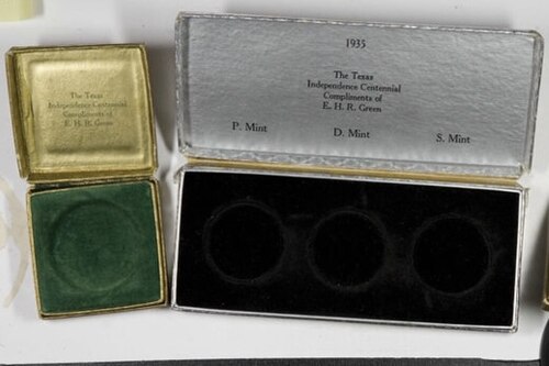 حاملان على شكل صدفة لعملات نصف دولار، أحدهما أخضر بفتحة واحدة والآخر أسود بثلاث فتحات.